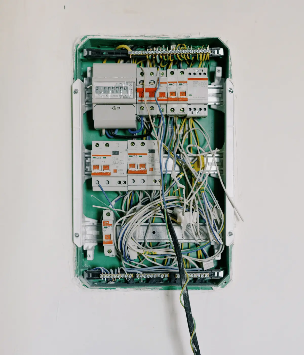 Tableau électrique mural ouvert, disjoncteurs et compteur avant mise en ordre du câblage.